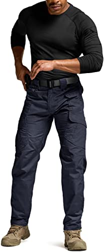 Men's dark navy tactical cargo pants shown on a male model from the front. Features multiple cargo pockets on thighs, a black belt, and a straight leg fit. Paired with a black long-sleeve shirt and tan boots.