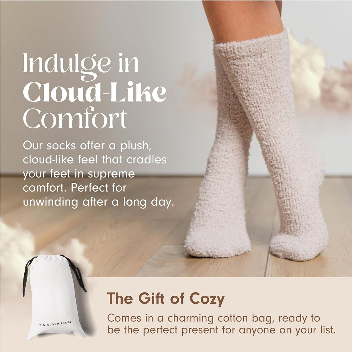 Promotional banner for plush cream-colored knee-high fuzzy socks worn on a person's legs, standing on light wood flooring. Text reads 'Indulge in Cloud-Like Comfort.' Bottom section shows a white drawstring cotton gift bag labeled 'T+M Cloud Socks' with 'The Gift of Cozy' tagline.