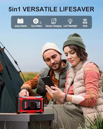 Two people in winter hats examine a smartphone while sitting near a tent outdoors, with a red and black portable jump starter device in the foreground. Banner reads '5in1 VERSATILE LIFESAVER' listing Jump Starter, Tire Inflator, Device Charging, LED Flashlight, and SOS., 3+ more images are available
