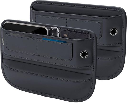 Two dark gray leather-like car seat gap filler organizers shown front and back. Each has multiple stitched pockets, a round grommet hole on the side, and a large open top slot. The front unit holds a phone, car key fob, and blue card.