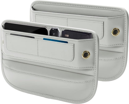 Two light gray leather car seat gap filler organizers shown together, one displaying open pockets holding a phone, card, and other items. Each has stitched compartments, a gold-toned grommet, and curved edges.