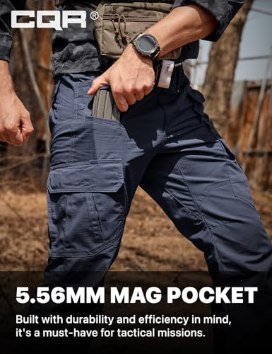 CQR tactical cargo pants in dark navy, shown on a person drawing a magazine from a large side cargo pocket. Text reads '5.56MM MAG POCKET - Built with durability and efficiency in mind, it's a must-have for tactical missions.'