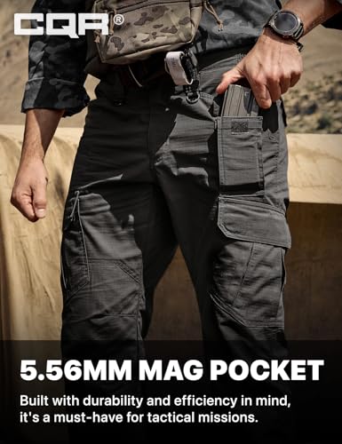 CQR tactical cargo pants in dark gray, shown on a person in an outdoor setting. A hand reaches into a side mag pocket holding an accessory. Text reads '5.56MM MAG POCKET - Built with durability and efficiency in mind, it's a must-have for tactical missions.'