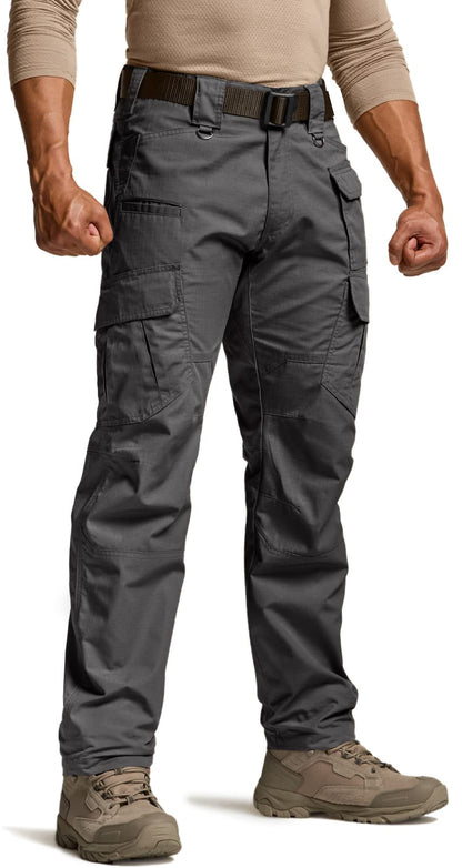 Men's dark gray tactical cargo pants shown from the front, featuring large side cargo pockets, a dark belt, and a straight leg fit. Worn with tan hiking boots and a beige long-sleeve shirt.