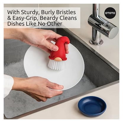 Hands scrubbing a white plate in a sink using a red gnome-shaped dish brush with white bristles and a tan face detail. OTOTO branded. Text reads 'With Sturdy, Burly Bristles & Easy-Grip, Beardy Cleans Dishes Like No Other'