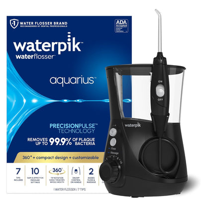 Waterpik Aquarius Water Flosser in black, shown beside its blue product box. Box reads 'waterpik waterflosser aquarius' and 'Removes up to 99.9% of plaque bacteria.' Device features a water reservoir, pressure dial, and attached handle with tip.