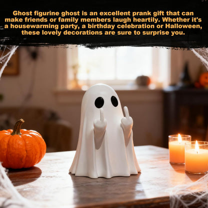 White ceramic ghost figurine with large black eyes and two raised middle fingers, displayed on a wooden table with orange pumpkins and lit candles in a Halloween-decorated room.