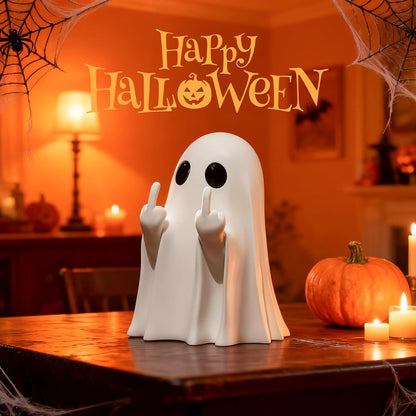 White ceramic ghost figurine with large black oval eyes and both middle fingers raised, sitting on a wooden table beside an orange pumpkin and lit candles. 'Happy Halloween' text arches overhead in orange lettering.