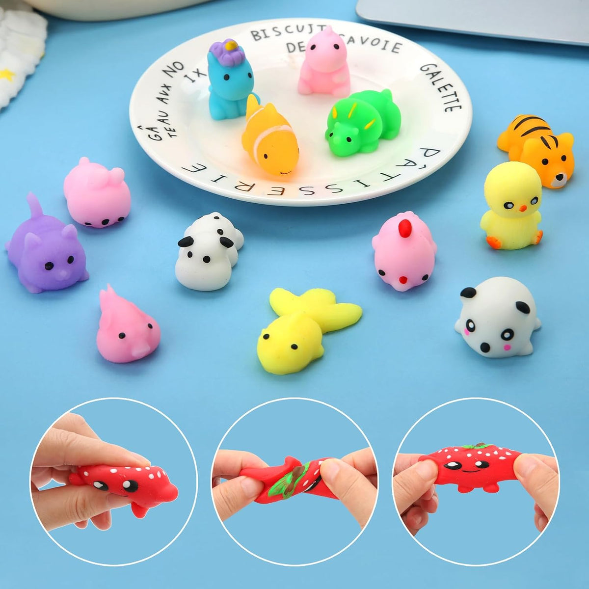 Colorful mini mochi squishy animal toys displayed on a white plate and blue surface, including a unicorn, pig, clownfish, dinosaur, tiger, duck, panda, and rabbit. Three inset circles show hands stretching a red strawberry-shaped squishy.