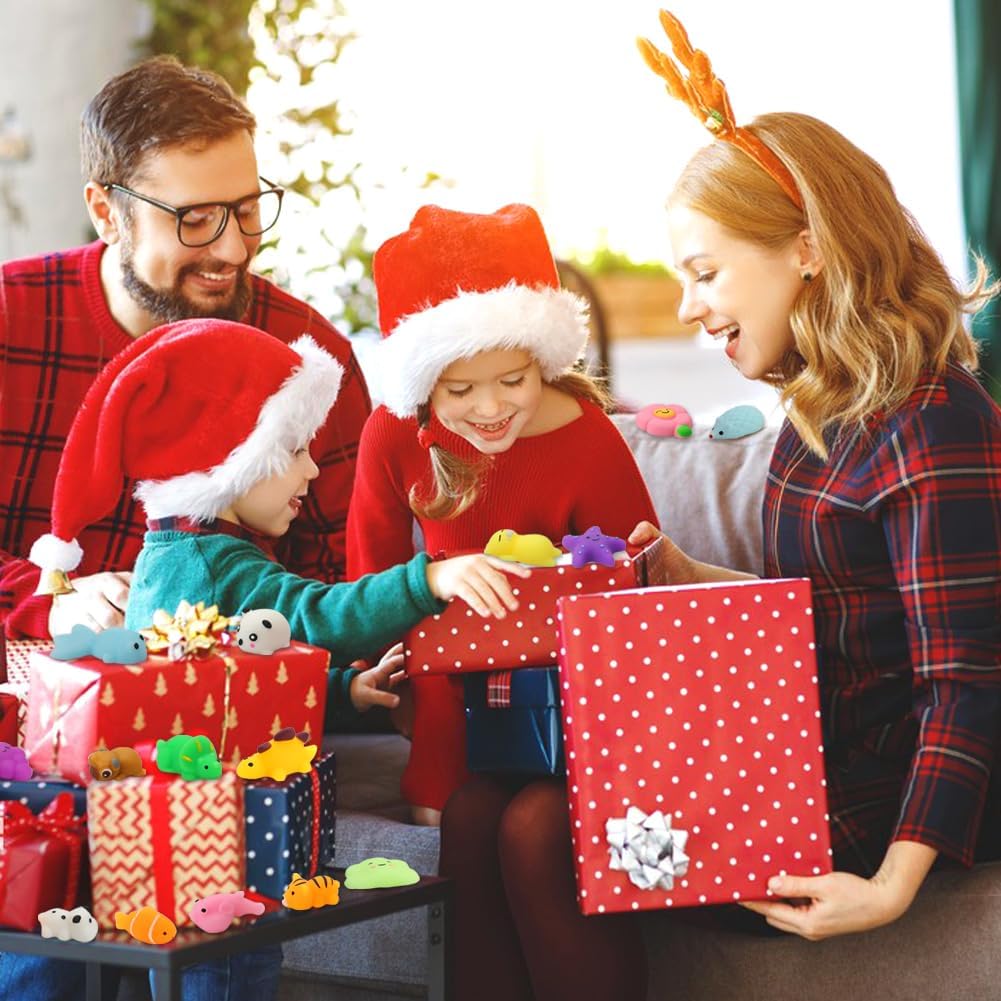 Family of four opening red polka-dot gift box filled with colorful small animal squeeze toys at Christmas. Wrapped presents on table are also covered in the multicolor squishy toys., 2+ more images are available 2+