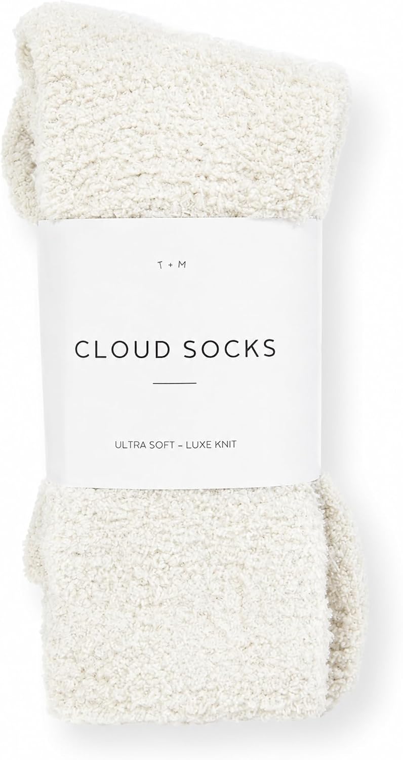 A pair of cream-colored fluffy knit socks folded and wrapped with a white paper band label reading 'Cloud Socks' and 'Ultra Soft - Luxe Knit' by T+M, shown on a white background.