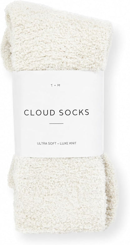 A pair of cream-colored fluffy knit socks folded and wrapped with a white paper band label reading 'Cloud Socks' and 'Ultra Soft - Luxe Knit' by T+M, shown on a white background.