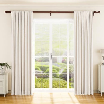 A dark bronze curtain rod mounted above a large French door window, holding off-white pinch-pleat curtain panels. The rod extends wall-to-wall with decorative finials on each end, shown in a bright living room setting.