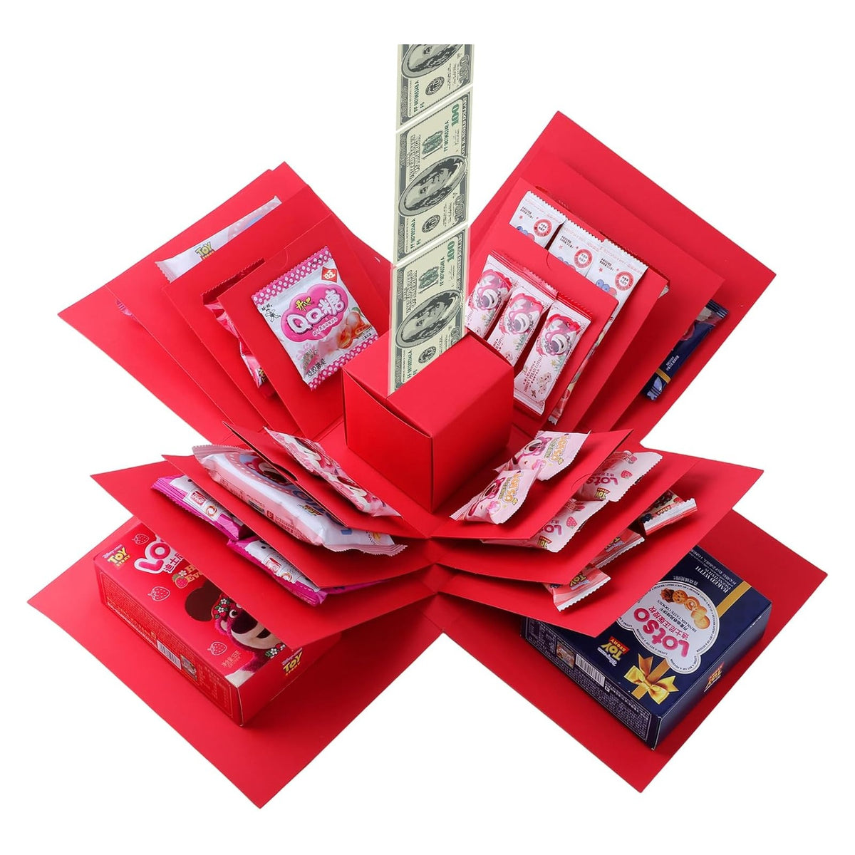 Red multi-layered explosion gift box shown fully opened, with panels fanned out in a star shape revealing assorted snacks and candies on each tier. A strip of dollar bill novelty paper extends upward from the red center box.